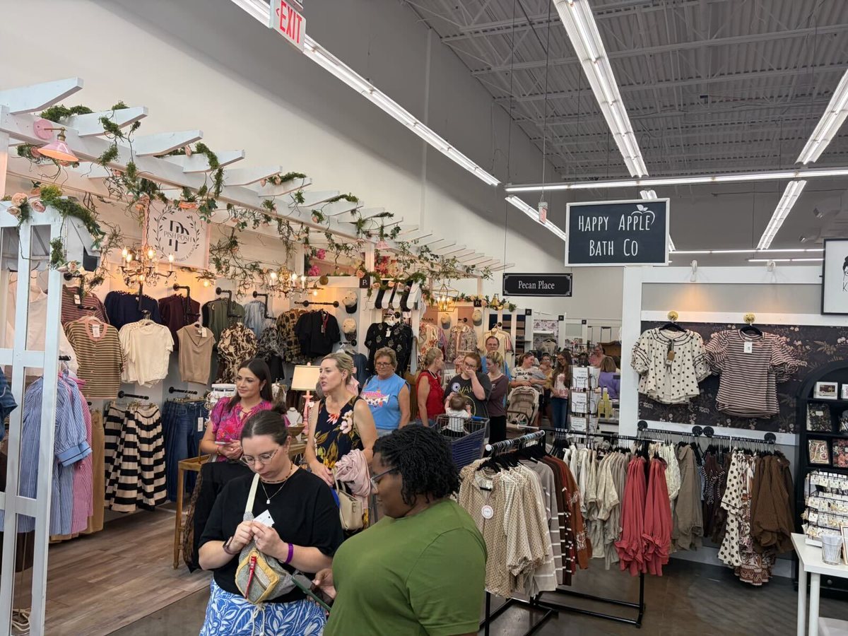 Shoppers on a multi-vendor boutique store, with individual vendor booths and signage