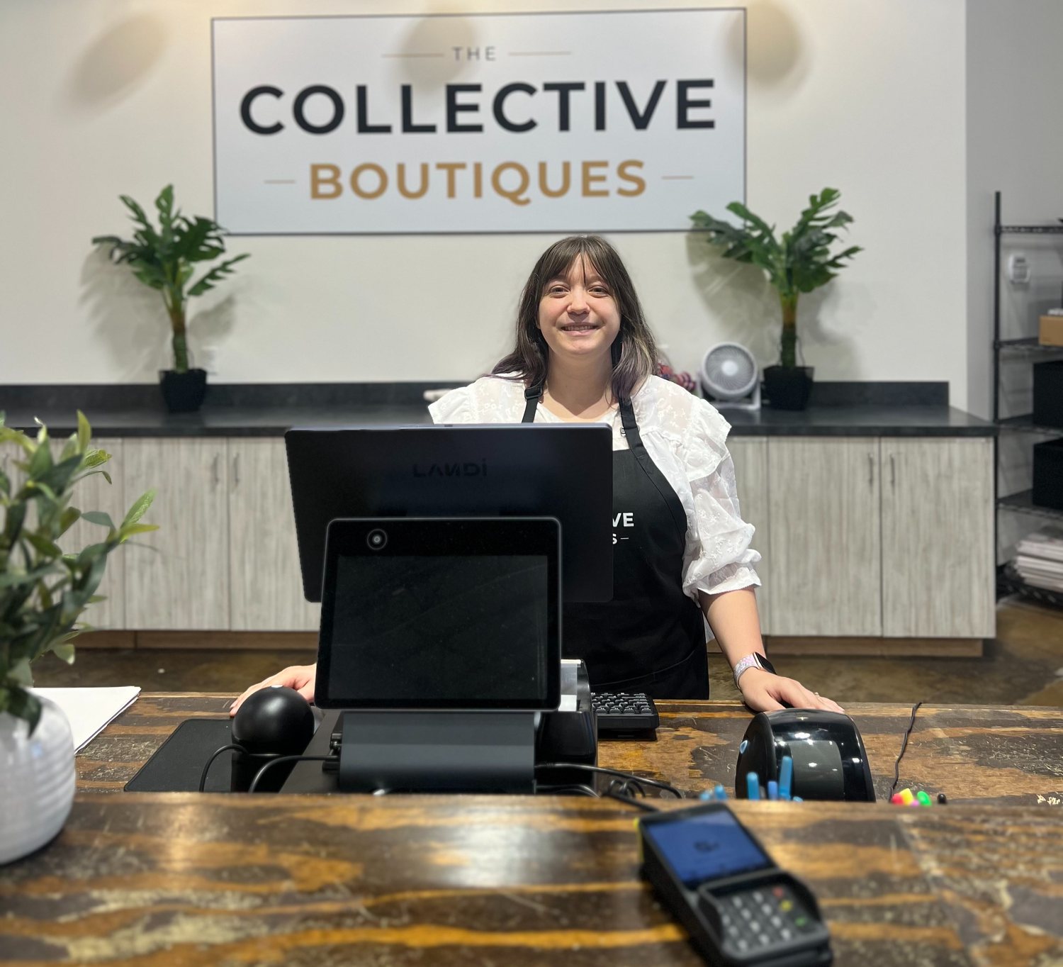 The checkout counter at The Collective Boutiques in Franklin: a Landi CX20 with its customer-facing display, a Dejavoo payment terminal, a label printer and a barcode scanner